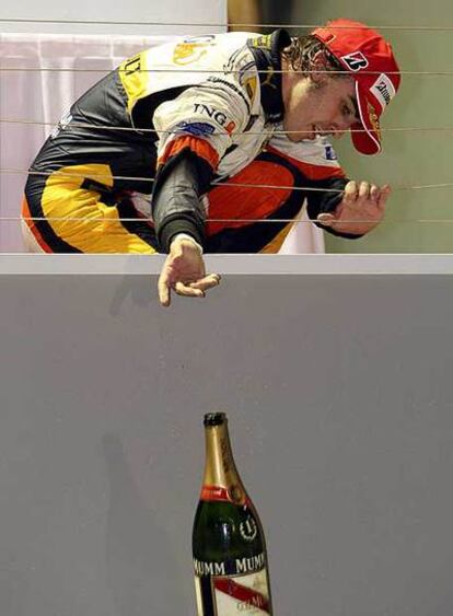 Fernando Alonso lanza a sus ingenieros una botella de champaña.