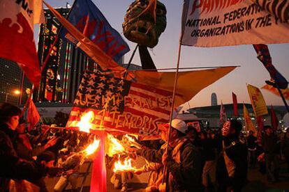 Manifestantes contra la Organización Mundial de Comercio queman una bandera estadounidense, ayer en Hong Kong.