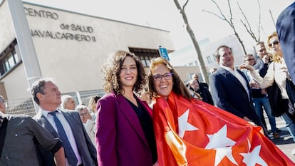 La presidenta madrileña, Isabel Díaz Ayuso, junto a una mujer envuelta en la bandera de la Comunidad de Madrid, el 23 de marzo, en la presentación del centro de salud Navalcarnero II.