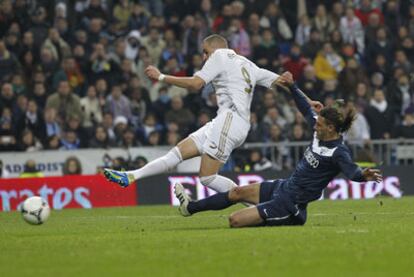 Karim Benzema scores Real's third despite a challenge from Málaga's Martín Demichelis.