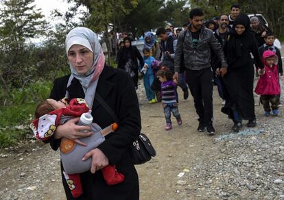 Uma mulher segura um bebê. É acompanhada por um grupo de imigrantes que cruzam a fronteira com a Grécia, em Gevgelija, Macedônia, 19 de outubro de 2015.