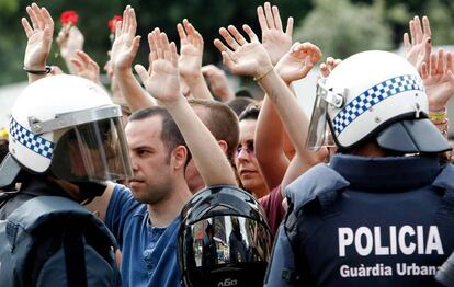 Jóvenes en la protesta del 15-M de la plaza de Catalunya alzan sus manos ante la Guardia Urbana.