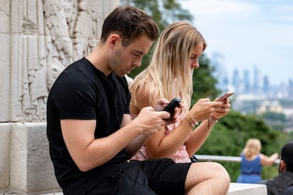 Dos jóvenes consultan sus teléfonos en Londres, Reino Unido