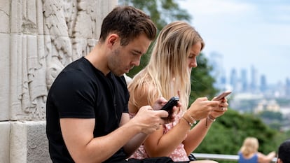 Dos jóvenes consultan sus teléfonos en Londres, Reino Unido.