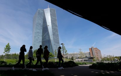 Cinco personas pasean por un parque con la sede del Banco Central Europeo al fondo, en Fráncfort.