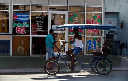 Dos personas pasan frente a una cafetería con imágenes en apoyo a la revolución cubana, en La Habana.