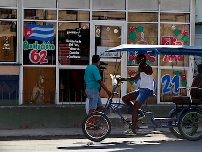 Dos personas pasan frente a una cafetería con imágenes en apoyo a la revolución cubana, en La Habana.