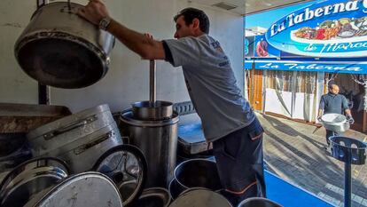 Un empleado de los restaurantes del Puerto Olímpico de Barcelona apila cacharros de cocina el día después del cierre durante dos años de los locales.