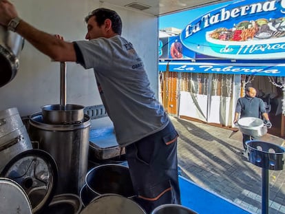 Un empleado de los restaurantes del Puerto Olímpico de Barcelona apila cacharros de cocina el día después del cierre durante dos años de los locales.