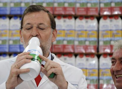 Rajoy bebe leche durante una visita a una planta de productos lácteos de Siero (Asturias).