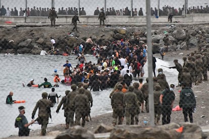 Paso de migrantes a nado por el espigón de la frontera de Marruecos con España en Ceuta, este martes.
