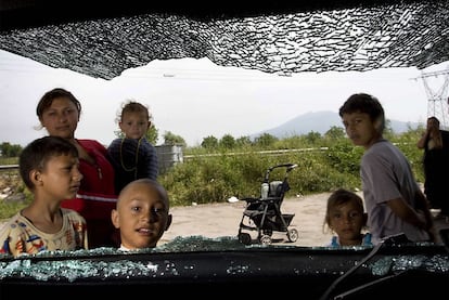 Varios niños se asoman por la ventanilla de un coche destrozado en un campamento de gitanos rumanos en Casoria, cerca de Nápoles.