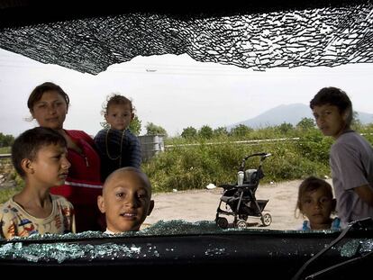 Varios niños se asoman por la ventanilla de un coche destrozado en un campamento de gitanos rumanos en Casoria, cerca de Nápoles.