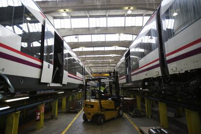 Un operario carga material en dos trenes que están siendo reparados.