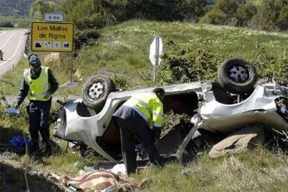 Guardias civiles examinan un coche que volcó ayer en Huesca, entre Ayerbe y el desvío de Riglos.