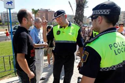 Un policía local lanza una advertencia a uno de los vecinos que ha protestado esta mañana durante una visita de Barberá al barrio de Patraix.