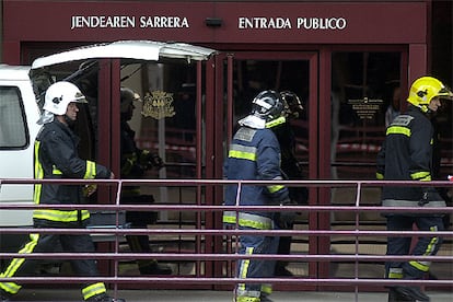 Tras apagar definitivamente el incendio, ocho dotaciones permanecen en el lugar del incendio para el desescombro de las zonas afectadas por las llamas y para apagar los rescoldos que quedan en distintas plantas. En la foto, varios bomberos pasan junto a la puerta principal del edificio de la Hacienda Foral de Guipúzcoa.