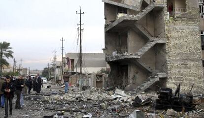Un grupo de personas permanece en el lugar donde ayer explosionó un coche bomba, en Bagdad, Irak, el pasado 12 de enero.