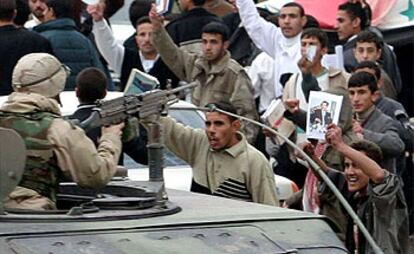 Un grupo de iraquíes muestra fotos de Sadam Husein y lanza consignas en su favor ante un soldado de EE UU que les apunta desde una tanqueta.