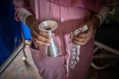 Tengen sostiene los elementos básicos del cuidado prenatal: un auricular para escuchar los latidos del corazón del bebé y una cinta métrica para medir el tamaño de la barriga.