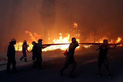 Bombers i voluntaris intenten apagar les flames a Rafina (Grècia).