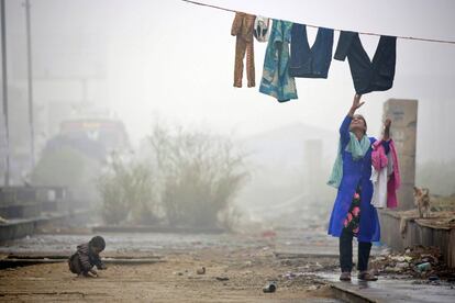 Una mujer recoge ropa tendida, en Delhi (India).