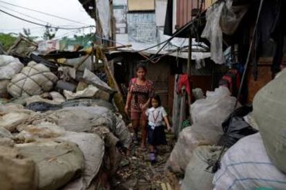 Weng Ruda, de 36 años y madre de tres niños, lleva a su hija a la escuela en el área depauperada de Quezón.