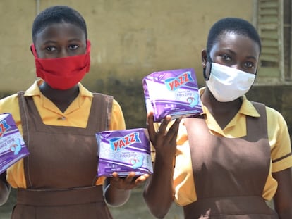 Dos jóvenes sujetan varios paquetes de compresas en Pediatorkope (Ghana).