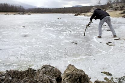 Un hombre intenta romper la gruesa capa de hielo que cubre el pantano del Pontón Alto, del que se abastece la ciudad de Segovia