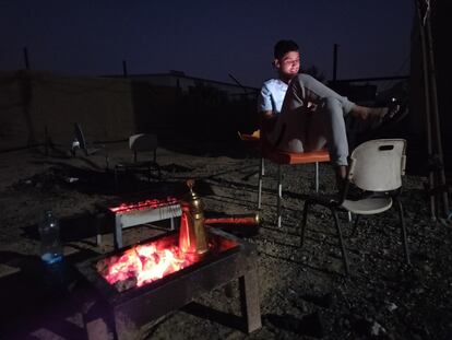 Un familiar de Riad El Shtiwi mira el móvil mientras se prepara el café, en el asentamiento beduino cerca de Tel Arad, en el desierto israelí del Neguev, el pasado junio.