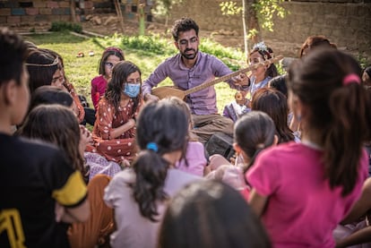 Fahad, narra la historia del “tembur” junto a niñas y niños retornados tras la liberación de Sinjar en manos del Estado Islámico, en el patio de la escuela de música de Mirzo Music Fundation en Khana Sore.