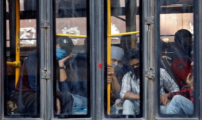 Trabajadores migrantes miran desde un autobús que les dirige a una estación de tren para regresar a su región india de Uttarakhand.