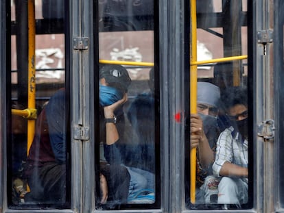 Trabajadores migrantes miran desde un autobús que les dirige a una estación de tren para regresar a su región india de Uttarakhand.