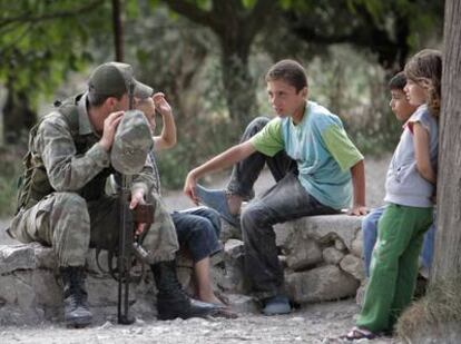 Un soldado turco habla con varios niños sirios en la frontera de Güveçci