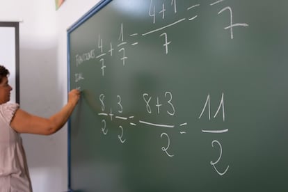 Una profesora hace operaciones matemáticas en una pizarra.