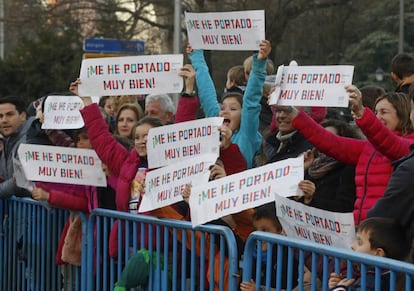 Varios niños con pancartas durante la tradicional cabalgata de Reyes en Madrid.