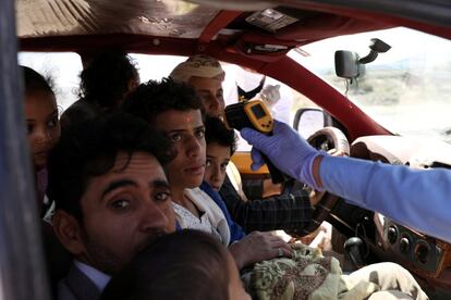 Un trabajador sanitario toma la temperatura de las personas que viajan en una furgoneta-taxi, en una de las entradas de la ciudad de Saná (Yemen).