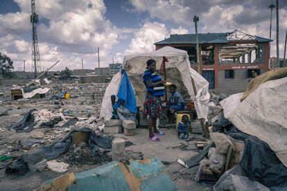 Una mujer y sus hijos, frente a la vivienda hecha de plásticos en la que ahora viven. Su hogar es una de las 16.500 viviendas derruidas, según el cálculo de investigadores del proyecto SLUMAP. 