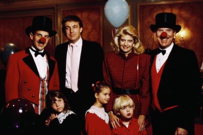 Trump con su primera esposa, Ivana, y dos de sus hijos, que van vestidos de rojo, en una función con payasos.