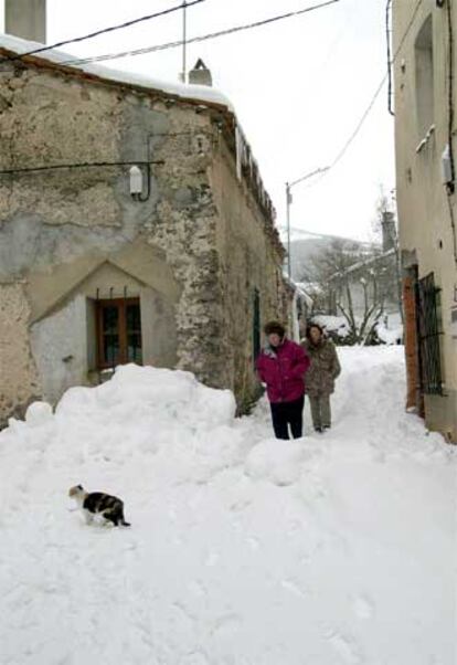 Dos mujeres caminan por una calle de Collado Hermoso (Segovia), totalmente cubierta de nieve.