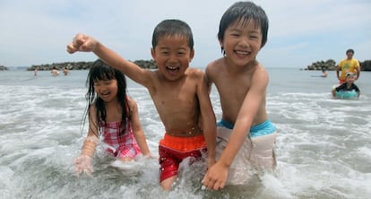 Tres niños se bañan en la playa de Nakoso.
