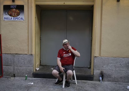 Un hincha del Liverpool sentado en una silla de plástico, en las cercanías de un bar del centro de Madrid, durante el partido.