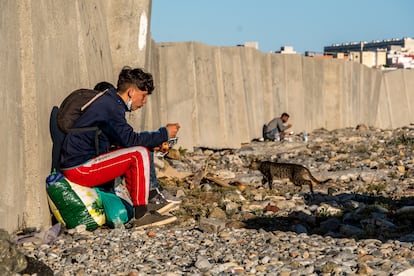 Dos chicos marroquíes aguardan escondidos en la playa ceutí de Calamocarro.