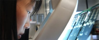 Una trabajadora de Shanghai examina los circuitos de un teléfono móvil en el departamento de investigación de la multinacional AT&T.