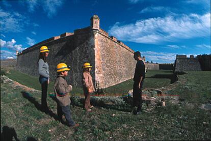 Niños con casco, dispuestos para la aventura, junto al foso de la fortaleza de Sant Ferran.