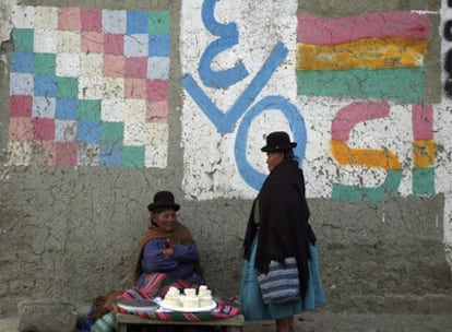 Dos mujeres indígenas conversan en El Alto, junto a una pintada en favor del presidente boliviano, Evo Morales.