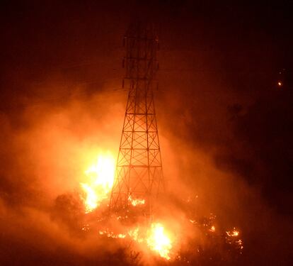 Las llamas del incendio Thomas consumen una torre de alta tensión en Montecito, California.