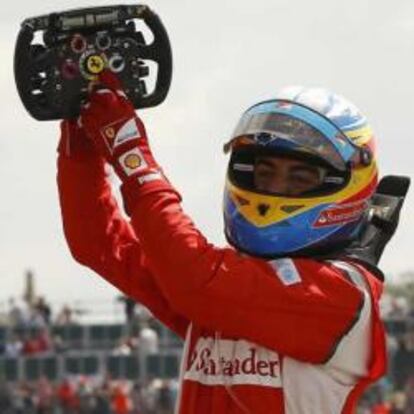 El piloto español de Fórmula 1, Fernando Alonso, señala el emblema de la escudería Ferrari en el volante de su vehículo, tras vencer en la carrera del GP de Gran Bretaña.