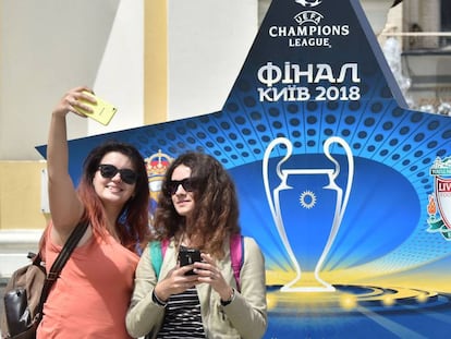 Dos mujeres se fotografían ante un logo de la final de Kiev.