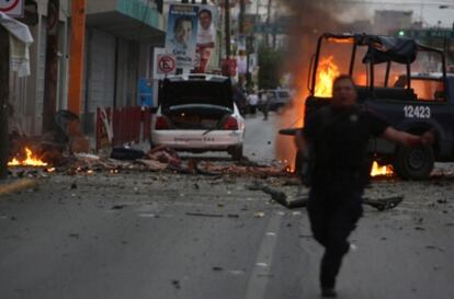 Un policía se aleja del lugar de la explosión del coche bomba que causó cuatro muertos el jueves en Ciudad Juárez